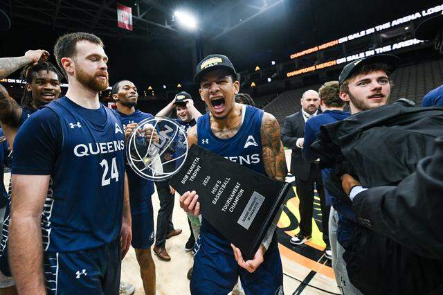 Nasir Mann (center, with trophy) celebrates with his Queens teammates after the Royals made it to the NCAA Tournament for the first time with a win in the ASUN championship game over Central Arkansas on March 8, 2026, in Jacksonville, Florida.